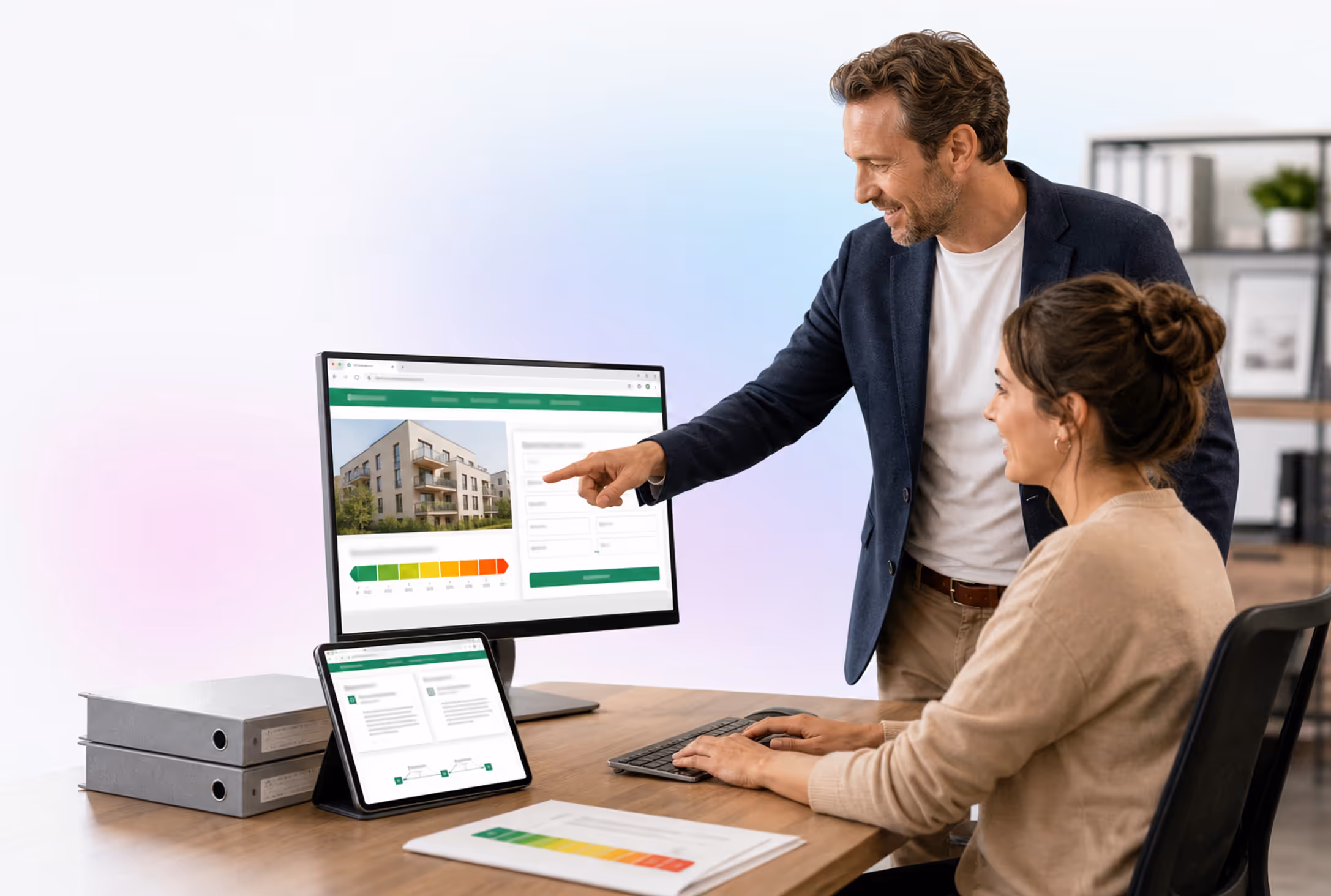 Makler- oder Hausverwaltungs-Team am Monitor mit energyausweis.de im Browser; Tablet mit Partnerbereich, Aktenordner und Energieausweis am Schreibtisch (Energyausweis API im Objektprozess)
